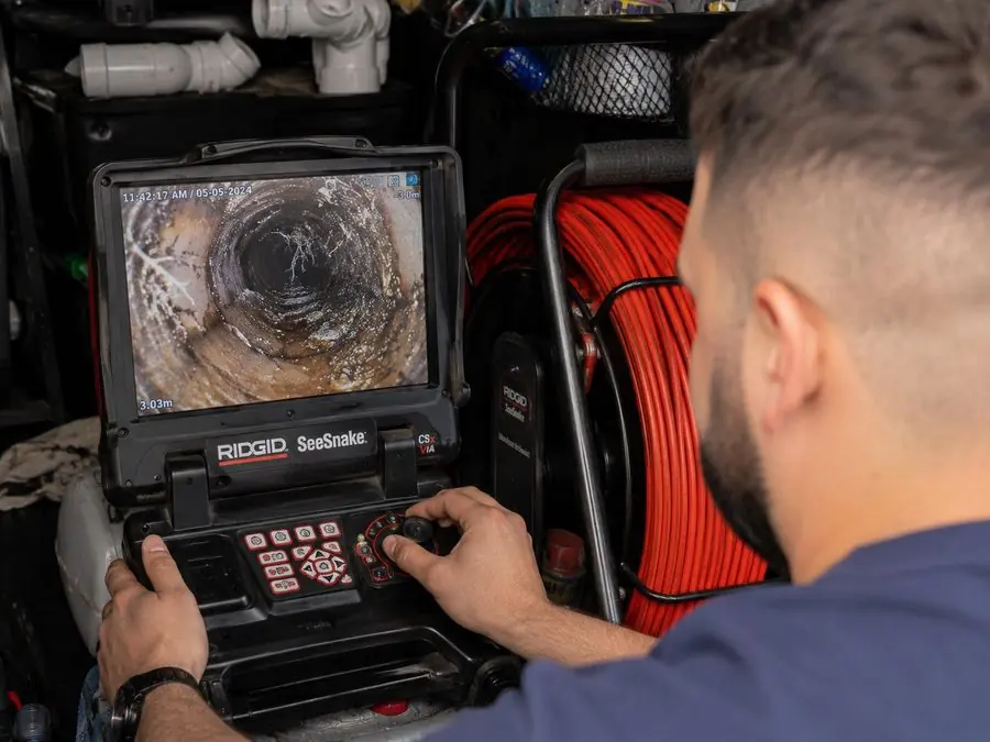 Plumber examining a CCTV drain inspection monitor, Chadstone